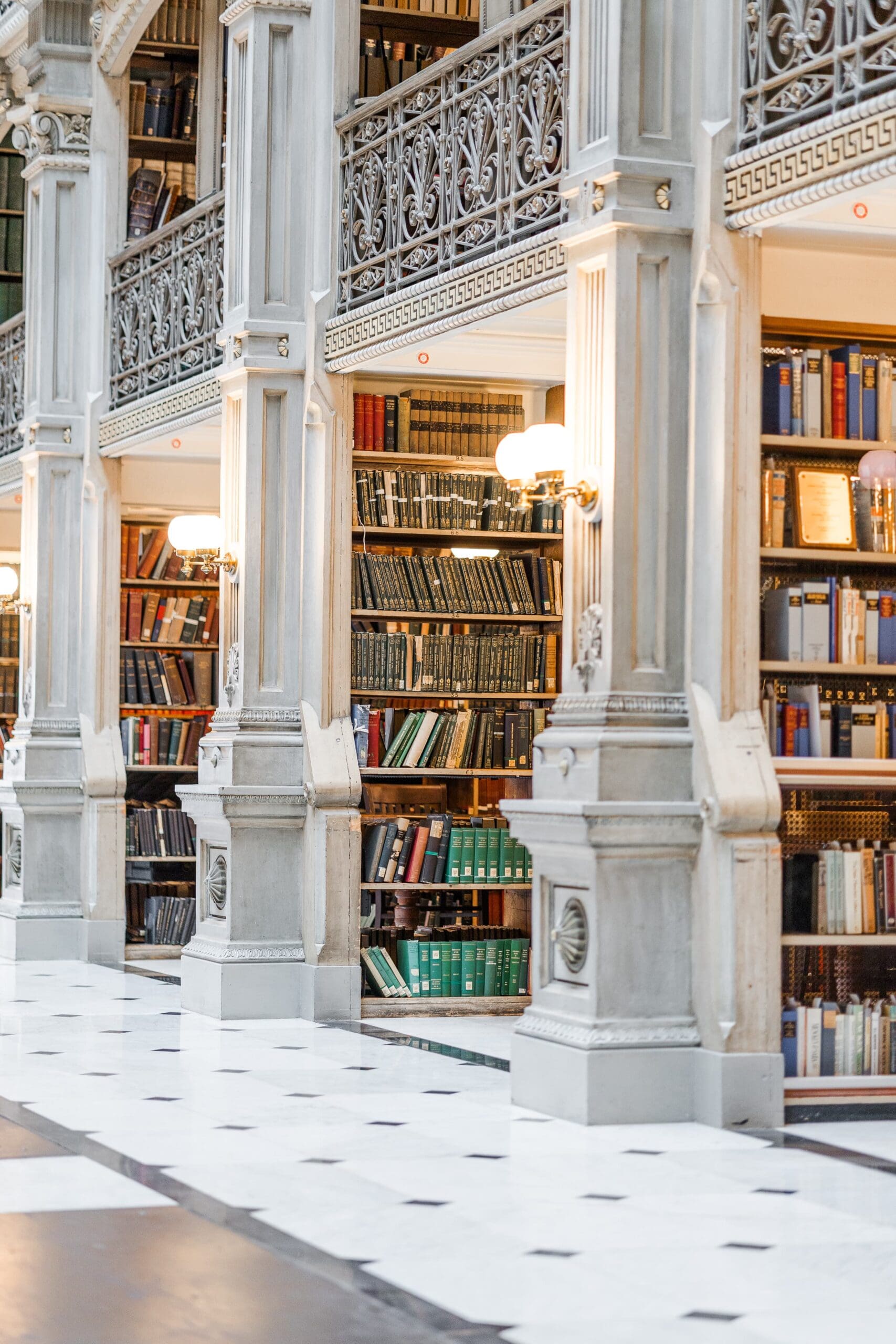 A grand library of book-filled aisles, adorned with ornate white pillars and warm lighting, exuding a serene atmosphere.
