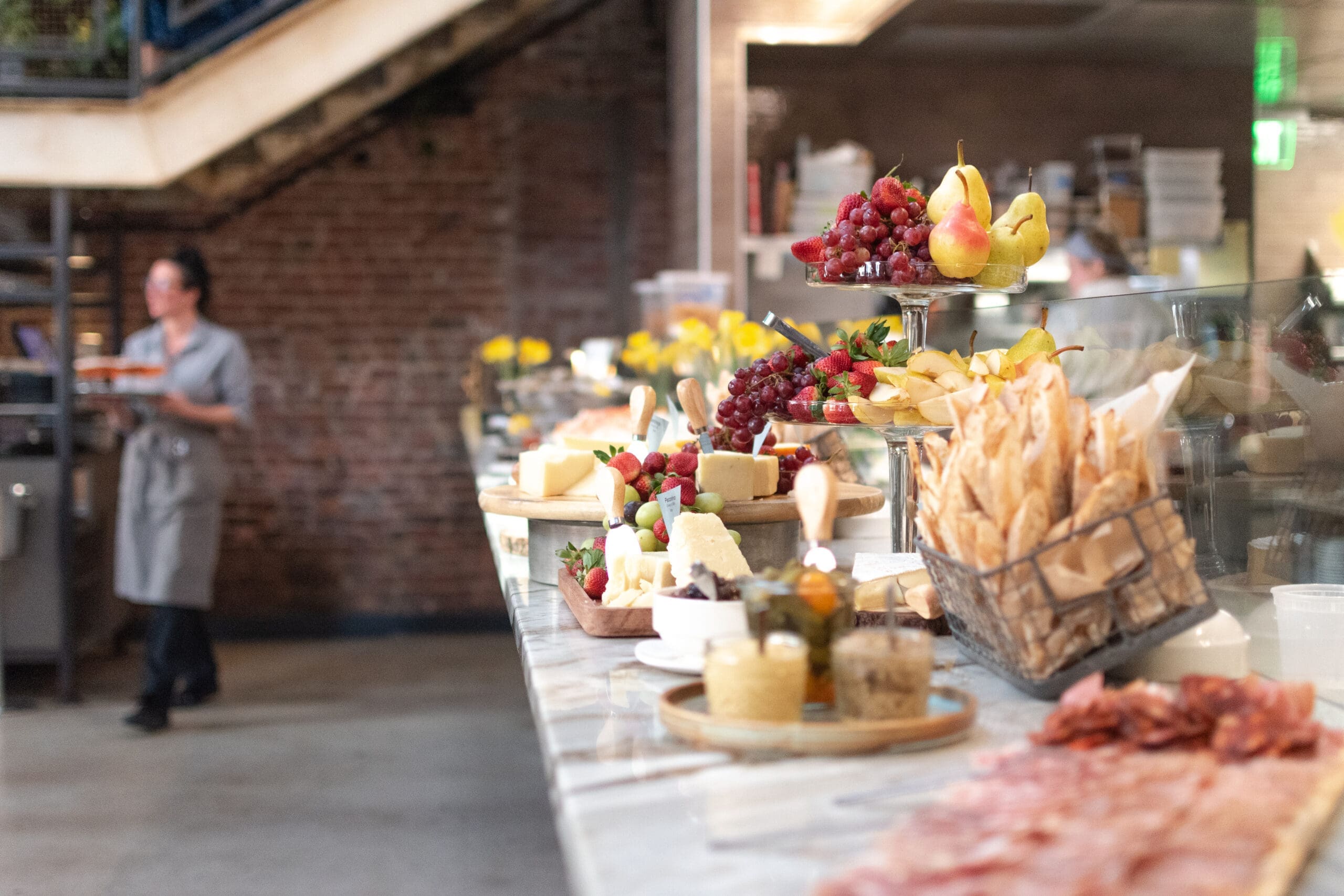 Restaurant bar with finger food on the table as a server walks buy with a tray of drinks.