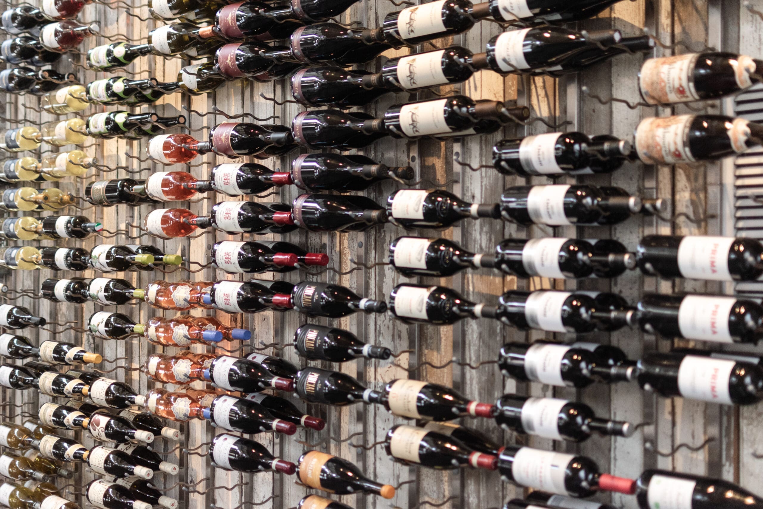 A wall-mounted wine rack filled with neatly arranged bottles of red and white wine, creating a sophisticated and organized display.