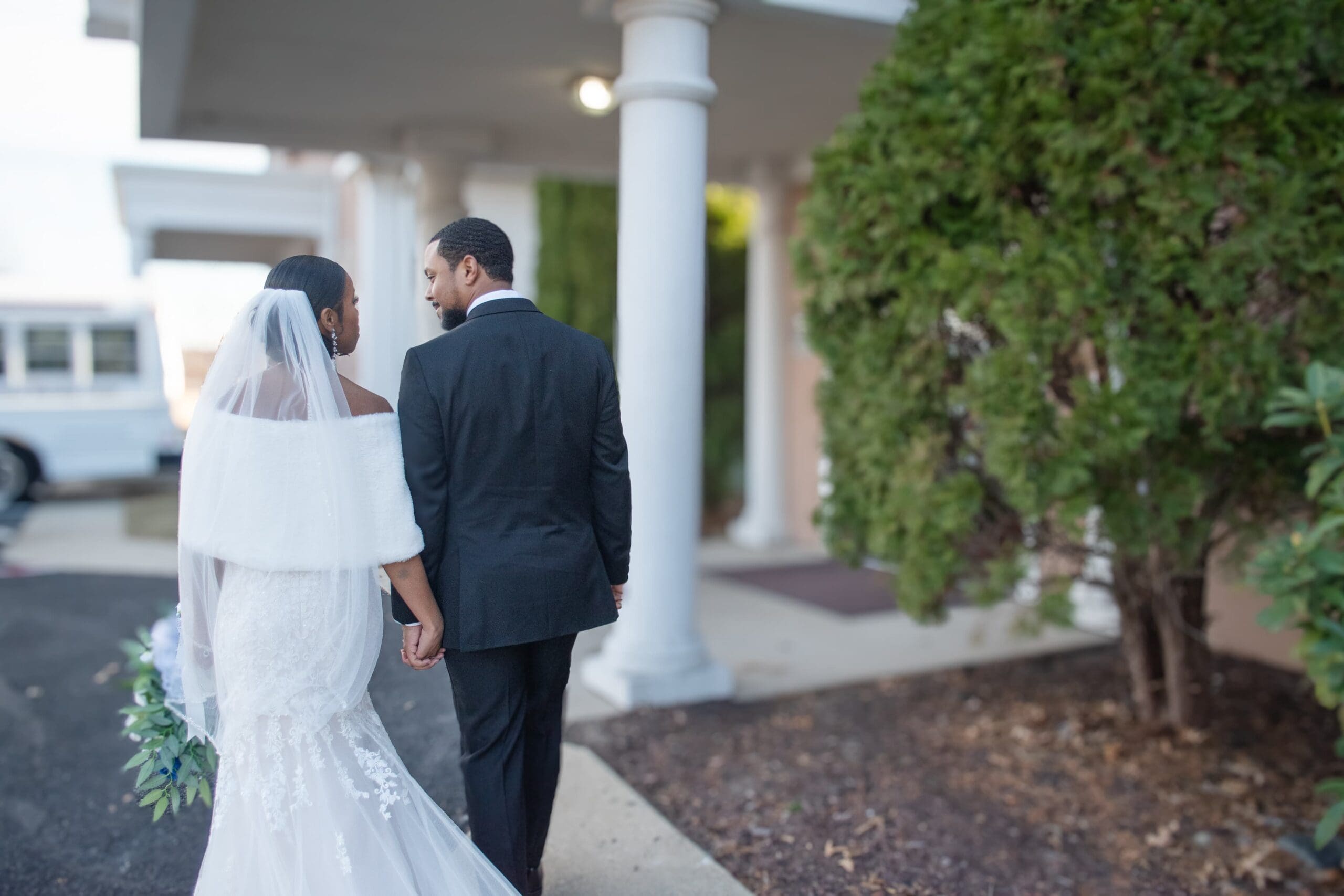 newlywed couple walks in front of their venue.