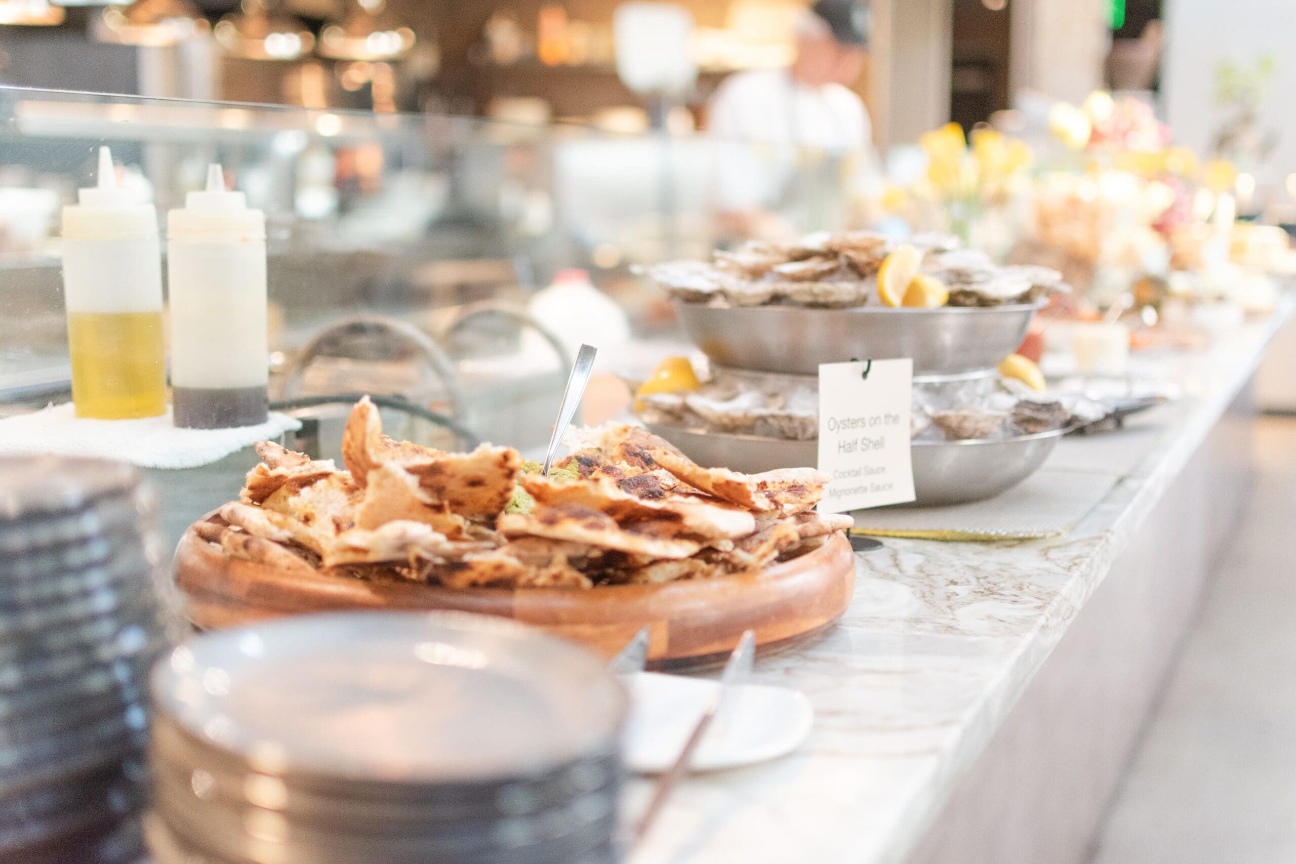 A tabletop counter with bread and oysters. Blurred plates in the foreground add depth.