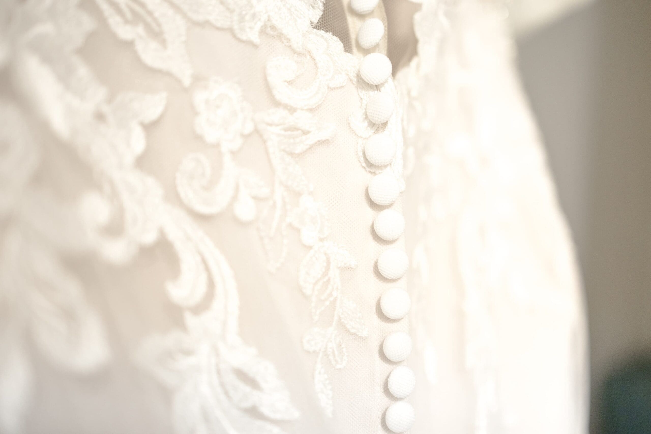 The back of a bridal wedding gown. White lace and buttons line the back.