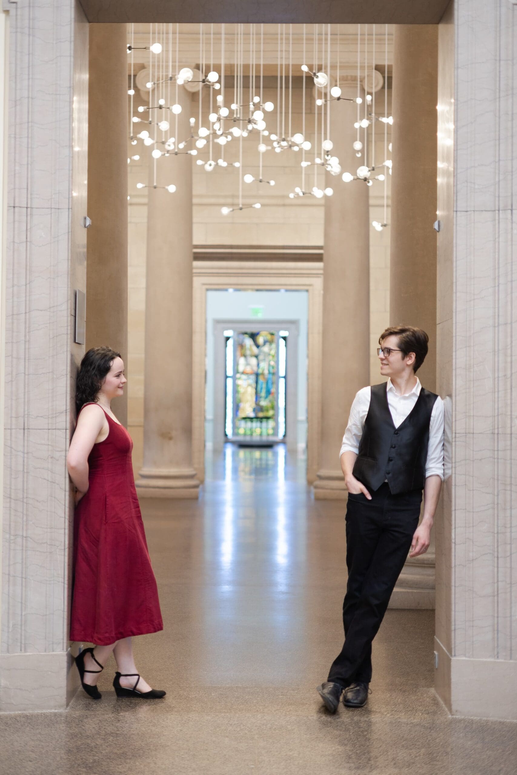 A couple leans against an open door threshold while floating lights hang above them. Creating a serene, romantic atmosphere.