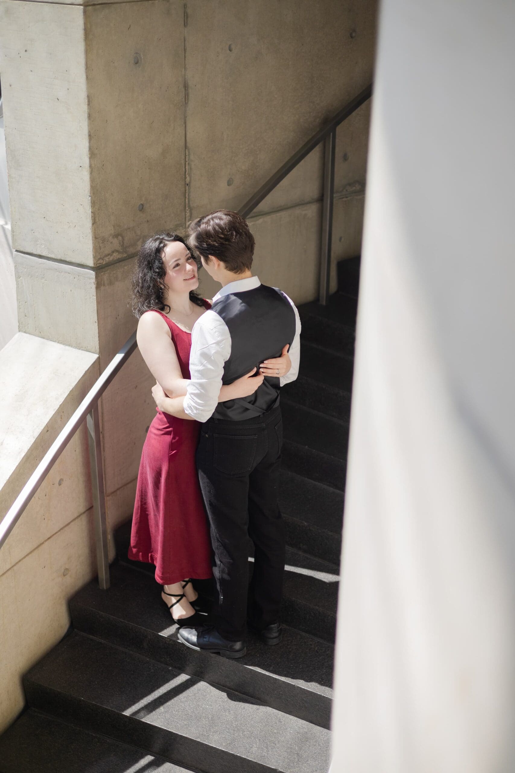 Couple hold each other close inside a staircase at the Baltimore Museum of Art. They gaze affectionately at each other, creating a serene, romantic atmosphere.
