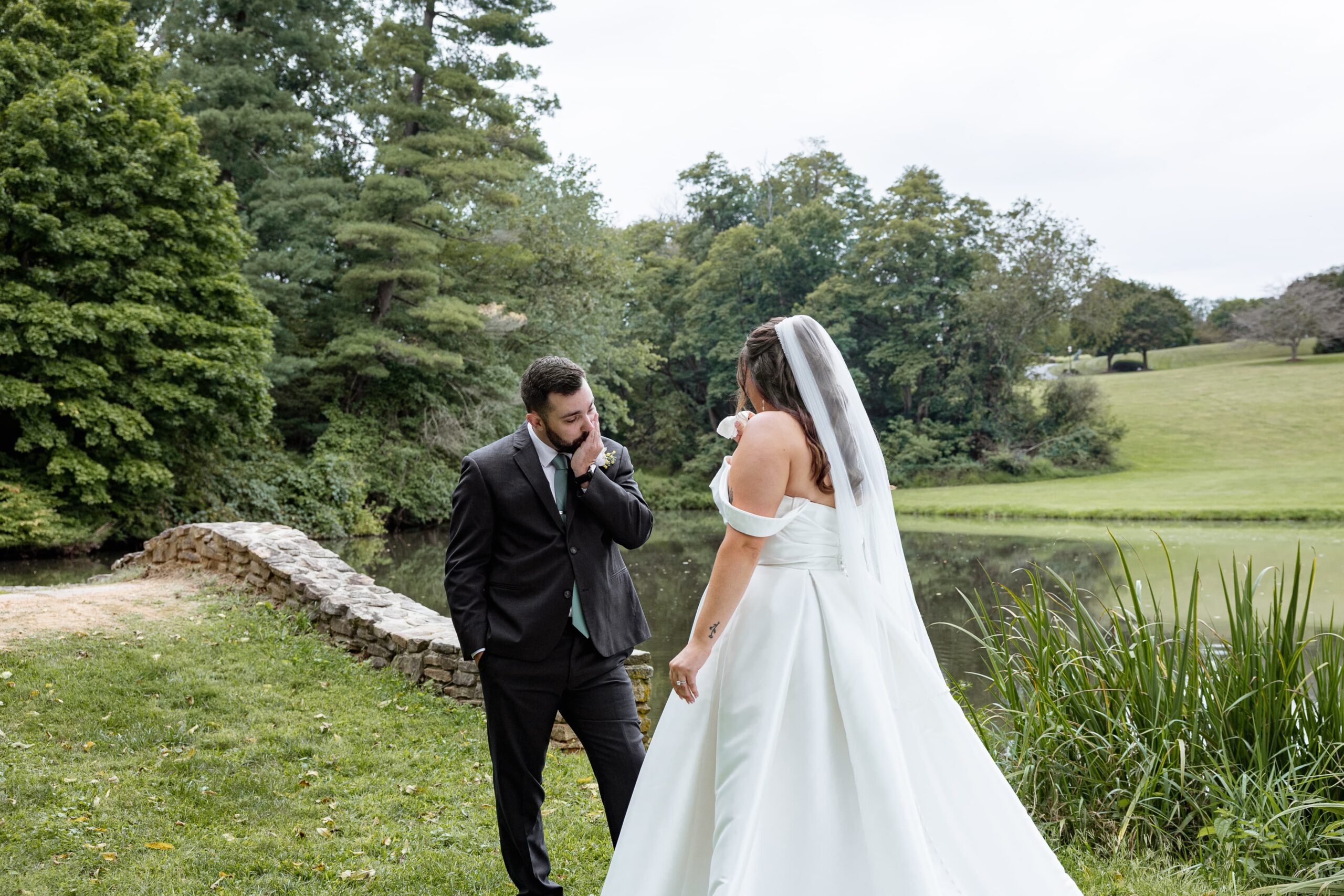 bride and groom share first look before wedding ceremony. Groom looks in awe at his bride in white.