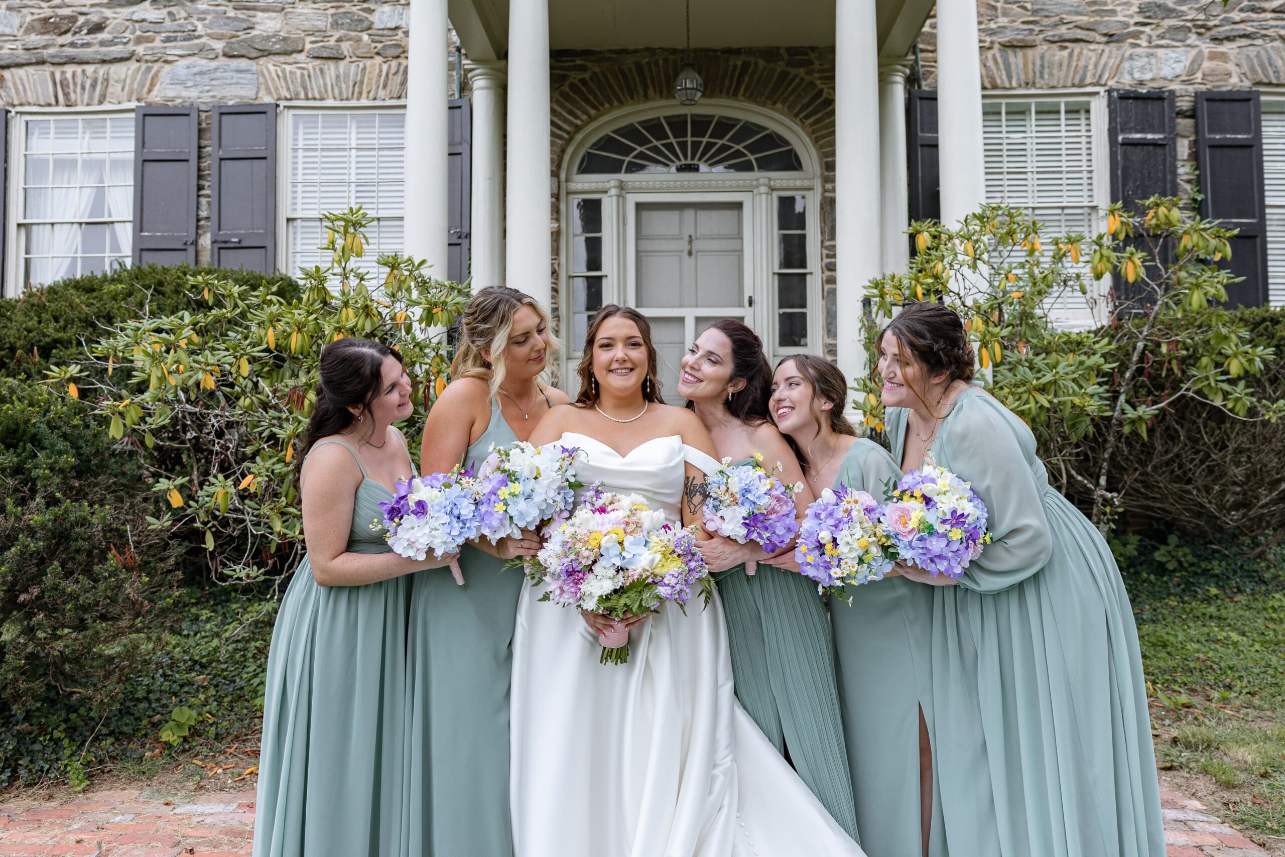 bridesmaids and bride huddle close and smile at bride with anticipation for her big day.